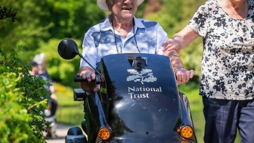 Close up of a visitor enjoying a day out in the gardens of a National Trust property in spring